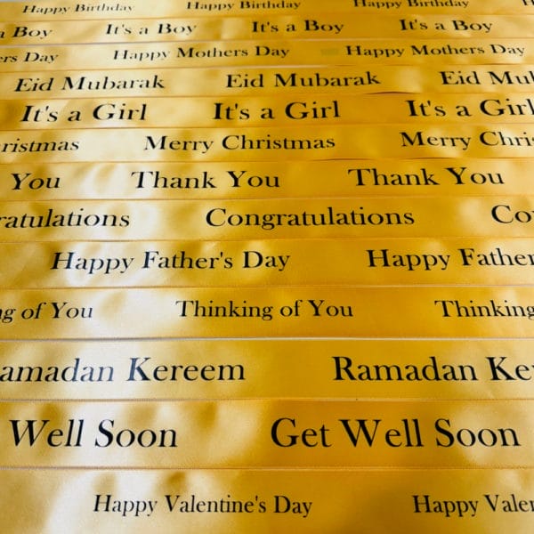 Ribbons Image. Printed golden stain ribbon with greetings. Includes "Happy Birthday," "It's a Boy," "Happy Mother's Day," "Eid Mubarak," "It's a Girl," "Merry Christmas," "Thank You," "Congratulations," "Happy Father's Day," "Thinking of You," "Ramadan Kareem," "Get Well Soon," and "Happy Valentine's Day." These ribbons add a beautiful touch to gift hampers.
